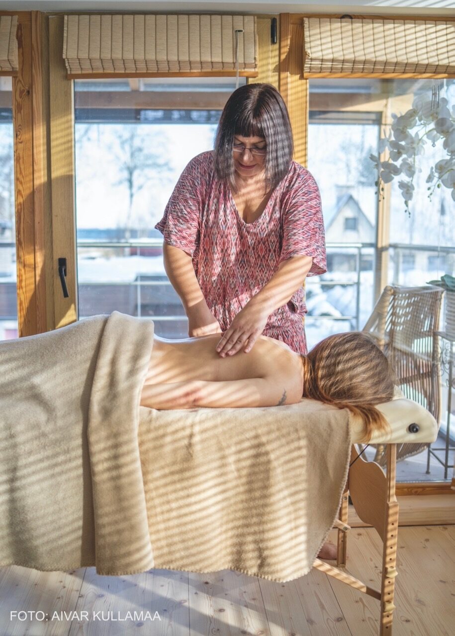 MER-kehatöö seanss: terapeudi käed massaaživad laual lebavat inimest