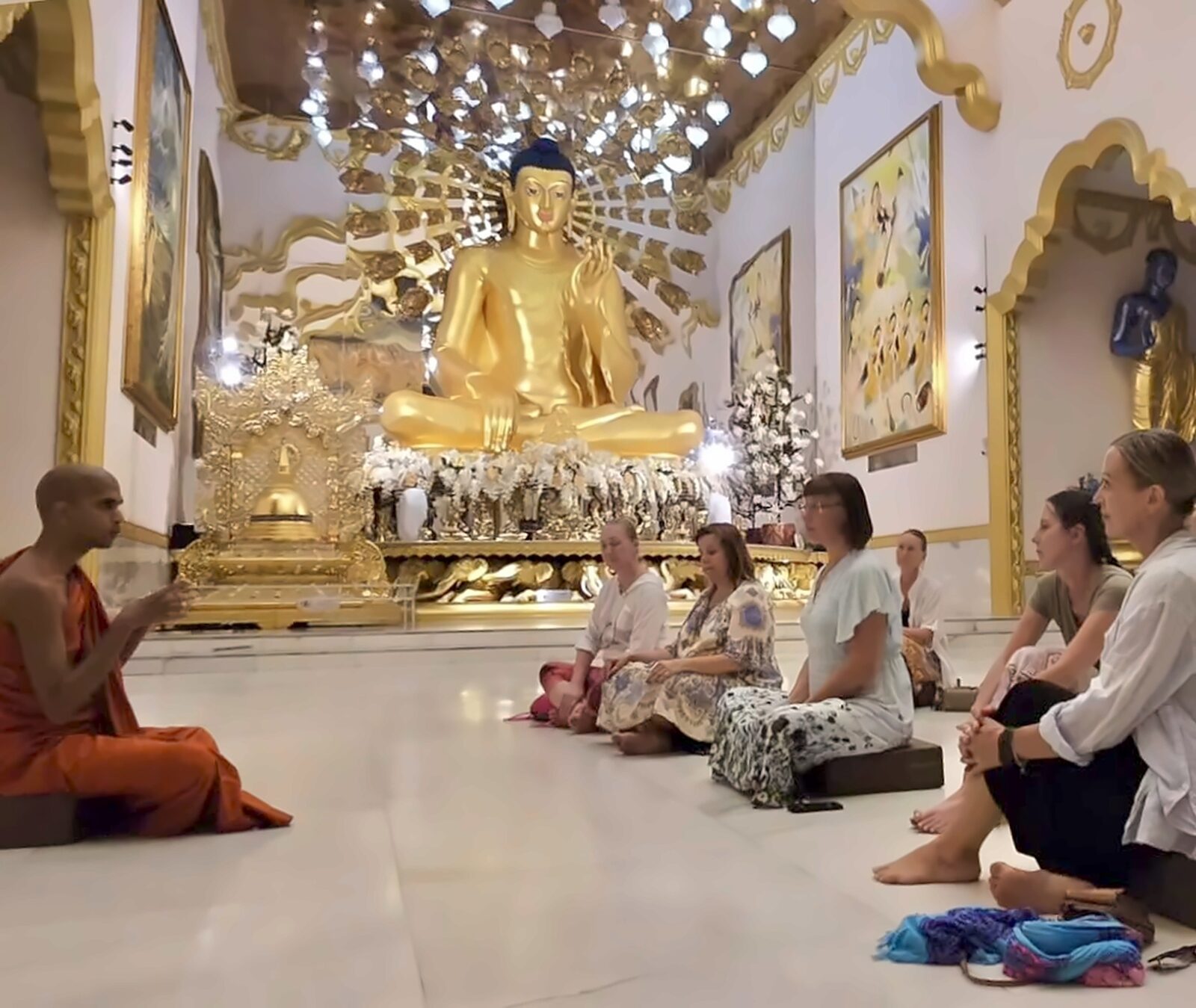 Budistlik munk õpetab meditatsioonirühmas Buddha kuju ees